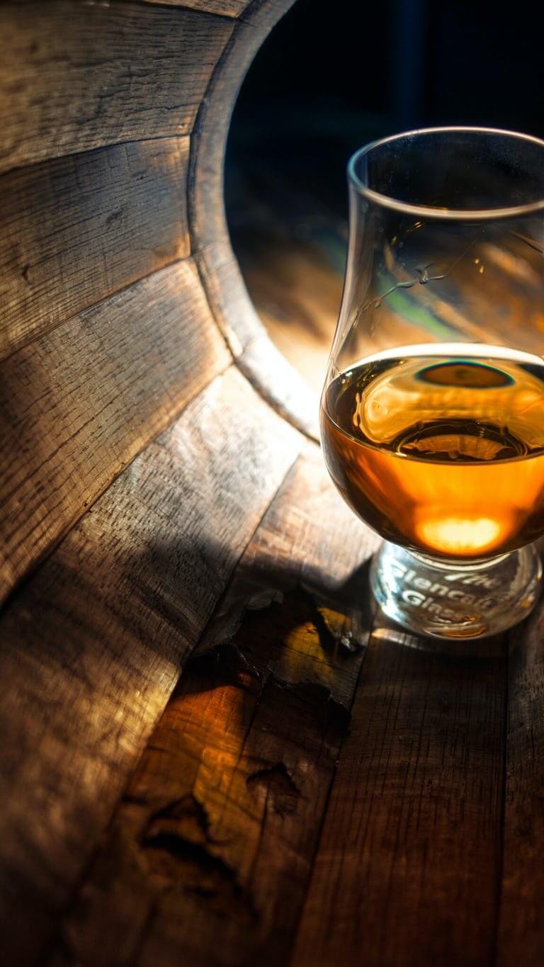 Glass of whiskey inside a wood barrel